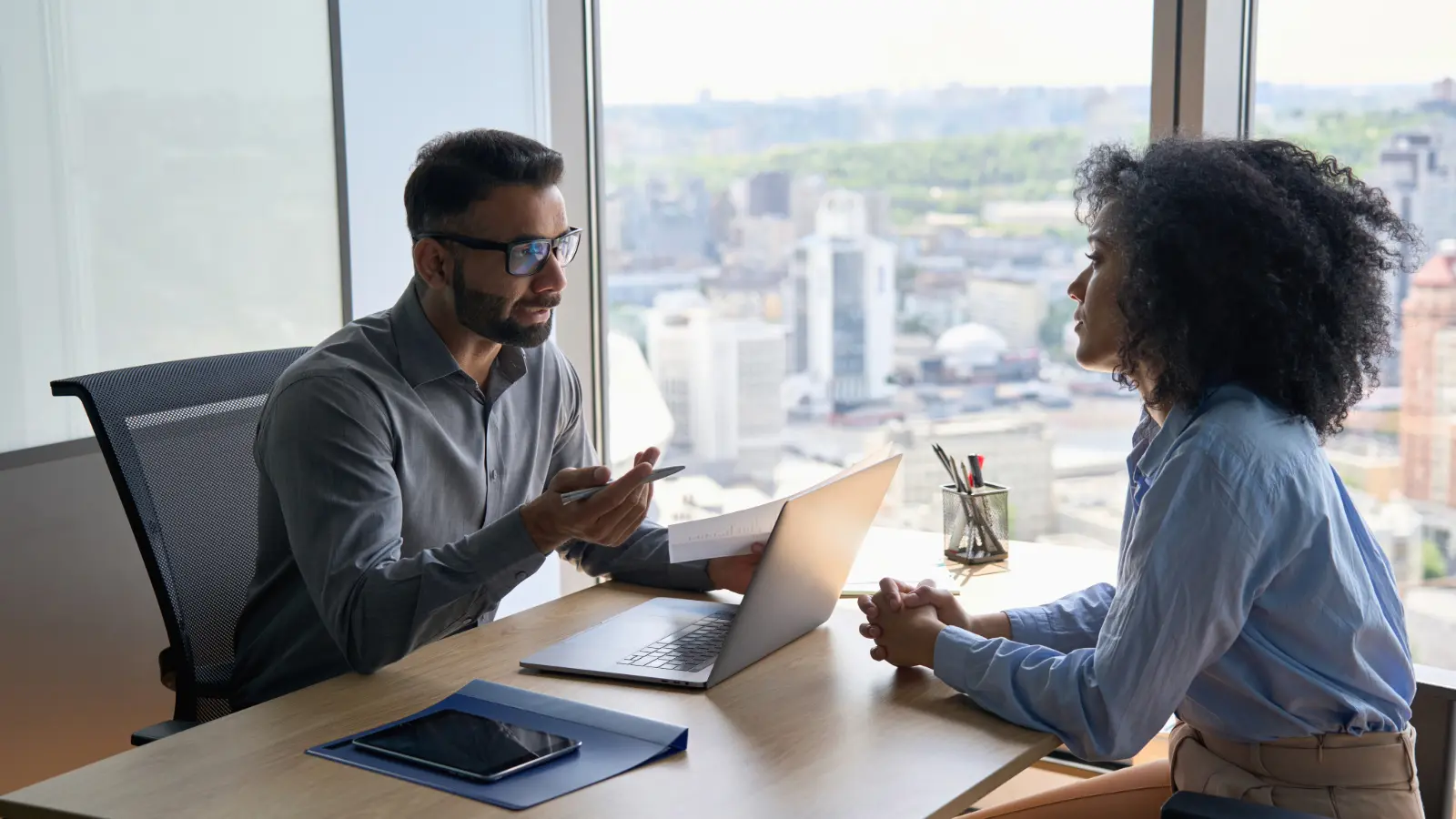 Male executive leader interviewing a female job candidate in an office setting.
